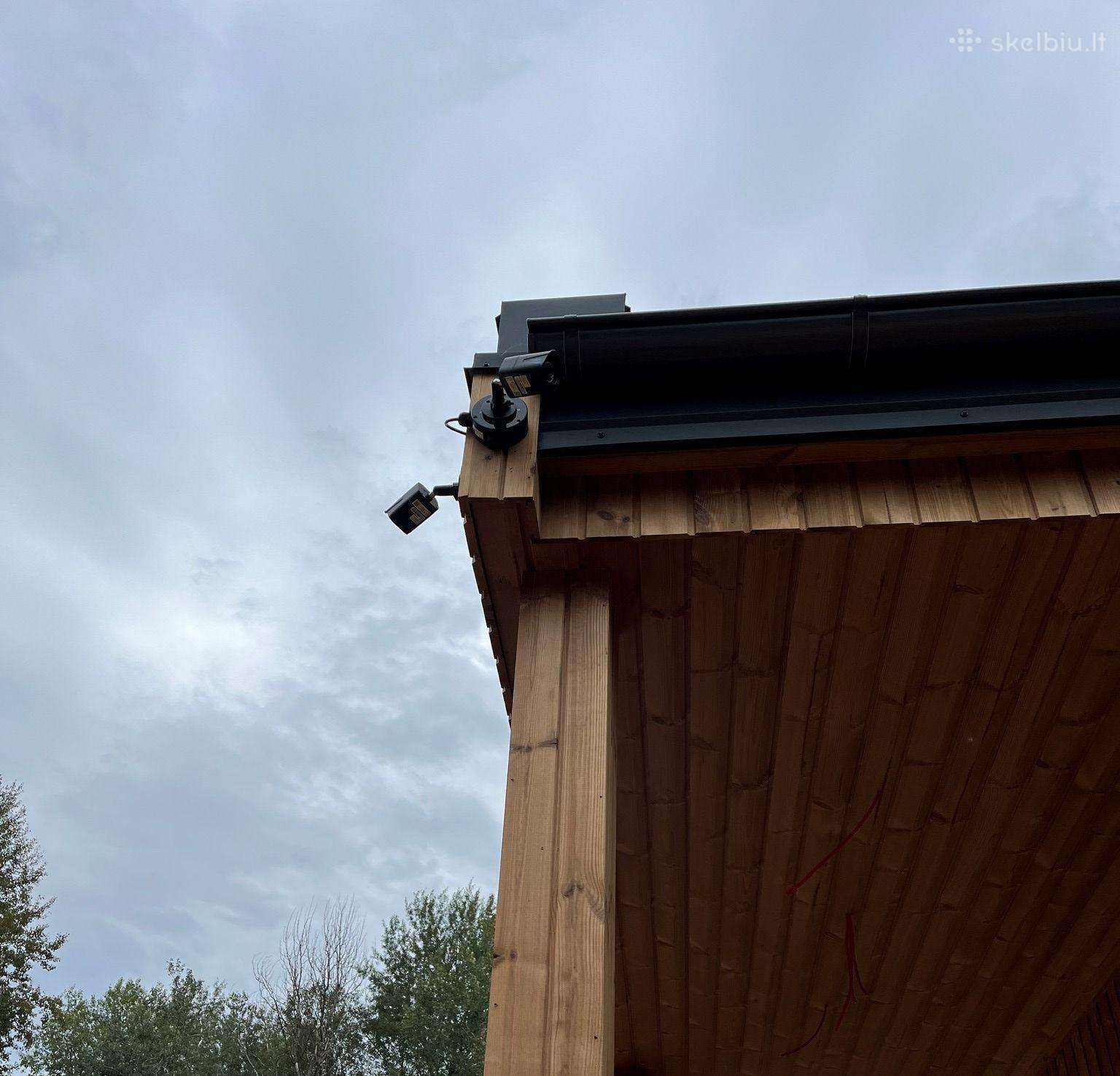 Vaizdo stebėjimo kamera įrengta ant medinio pastato kampo – profesionalus montavimas.